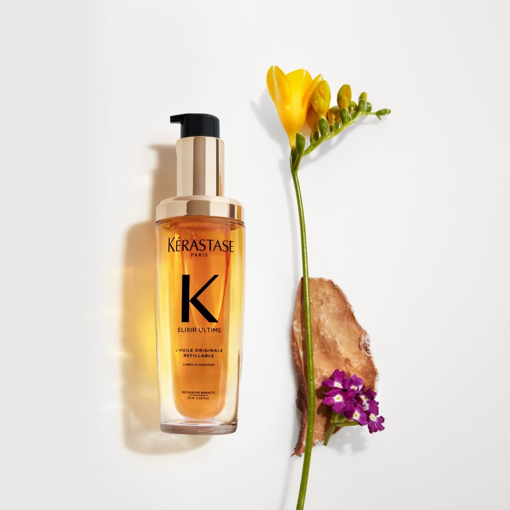 Chronologiste Huile de Parfum hair oil - featuring an artful blend of addictive fragrances mingling cedar, magnolia, and tea rose - is being held between two hands.